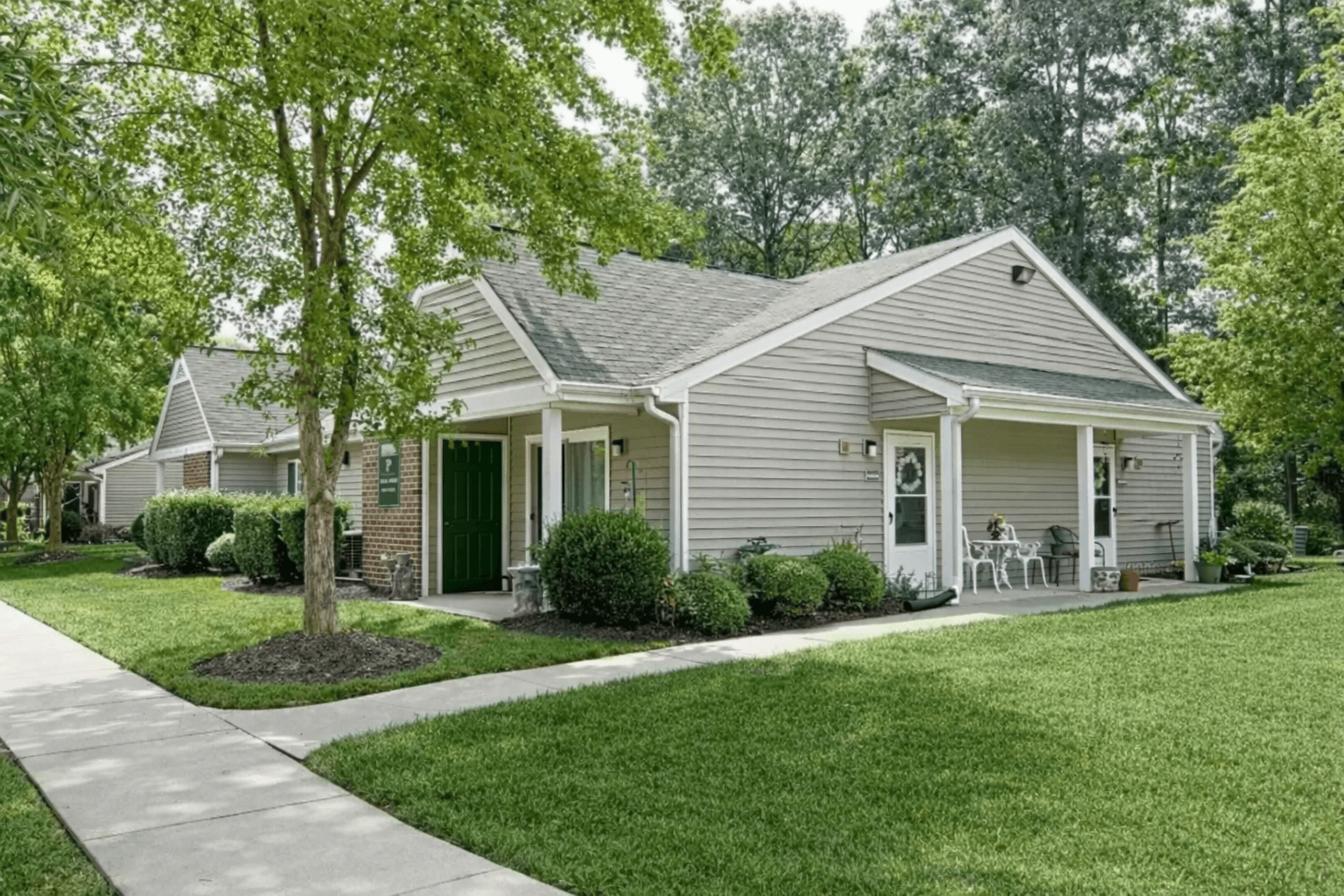 A house with a green lawn and a tree in front.